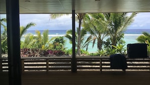 Una habitación con vista al océano, palmeras y una terraza de madera.