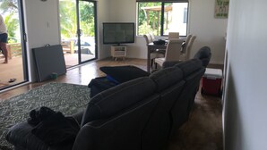 Una sala de estar con una televisión de pantalla plana grande, un sofá, una mesa de centro y un comedor con una mesa y sillas.