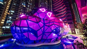 A spherical structure with a geometric design, illuminated by pink and blue lights, situated in an urban setting with high-rise buildings in the background. - Comfort & Cozy Family Suite (Ampang)