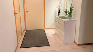 A hallway with a door, a small plant on a white console, and a mirror on the wall. - City center apartment for city people (Kesklinna linnaosa)
