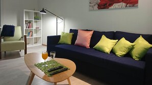 A living room with a dark blue sofa, green and pink cushions, a wooden coffee table, and a bookshelf. - City center apartment for city people (Kesklinna linnaosa)