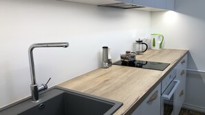 A modern kitchen with a built-in sink, a coffee maker, and a kettle on the countertop. - City center apartment for city people (Kesklinna linnaosa)