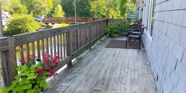 A wooden deck with a railing, potted plants, and outdoor furniture.
