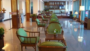 A hotel lobby with rows of wicker chairs and tables, a reception desk, and a bar area. - Tangerine Ville Hotel (Fang)