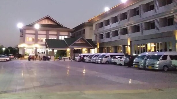 A hotel with multiple floors, a parking lot with several cars, and a well-lit entrance. - Tangerine Ville Hotel (Fang)