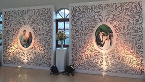 A hallway with ornate wall panels featuring circular photographs and a vase with flowers. - Tangerine Ville Hotel (Fang)