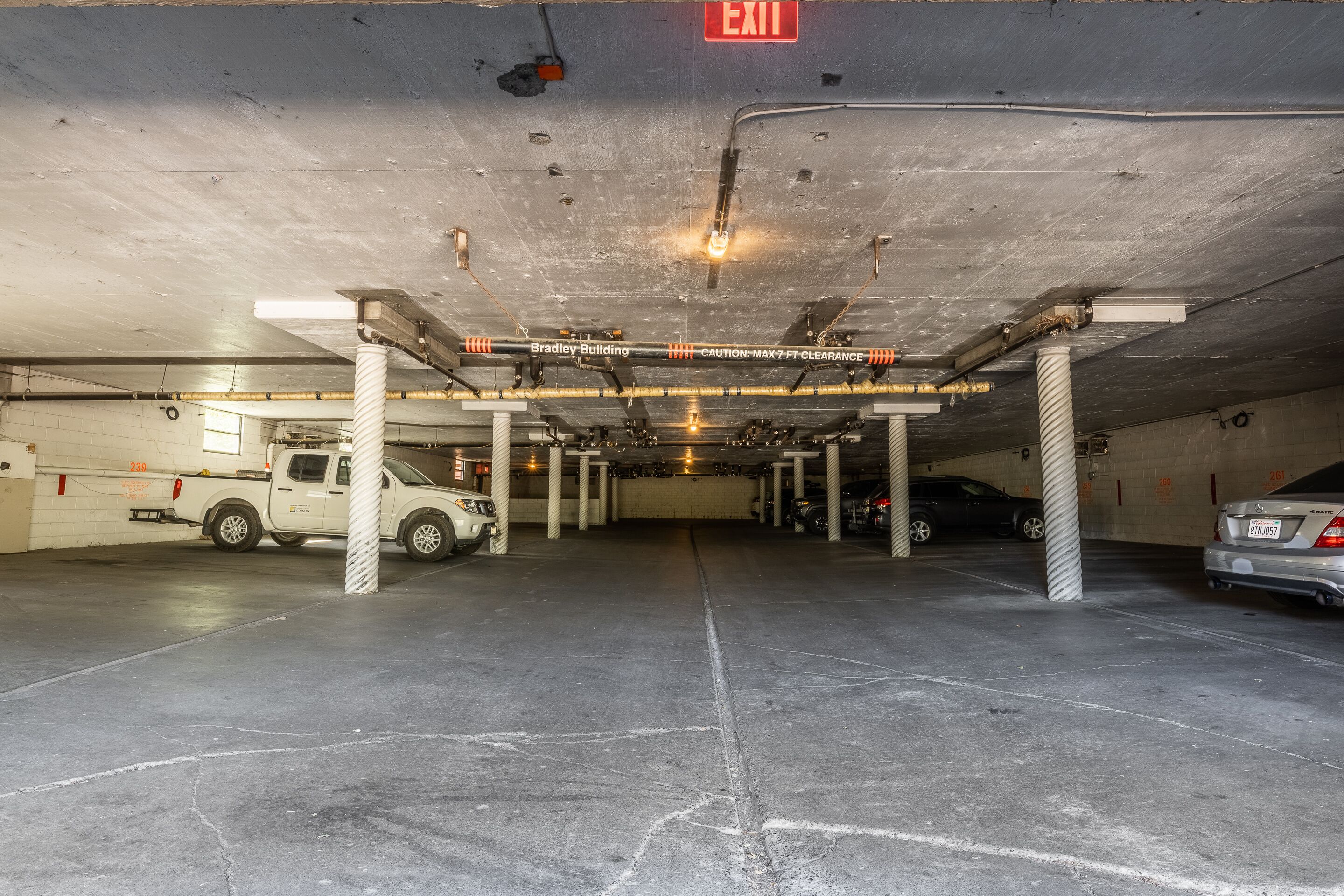 An underground parking garage with concrete pillars, a white pickup truck, and a silver car parked.