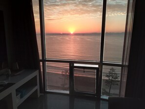 A room with a large window overlooking a sunset over the sea. - Pohang Valentine Hotel (Pohang)
