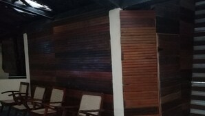 A room with wooden panel walls, a blue carpet, and wooden chairs with woven seats. - Rangala Hostel (Rangala)