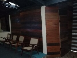 Habitación con paredes de madera, alfombra azul y sillas de madera con asientos de mimbre.