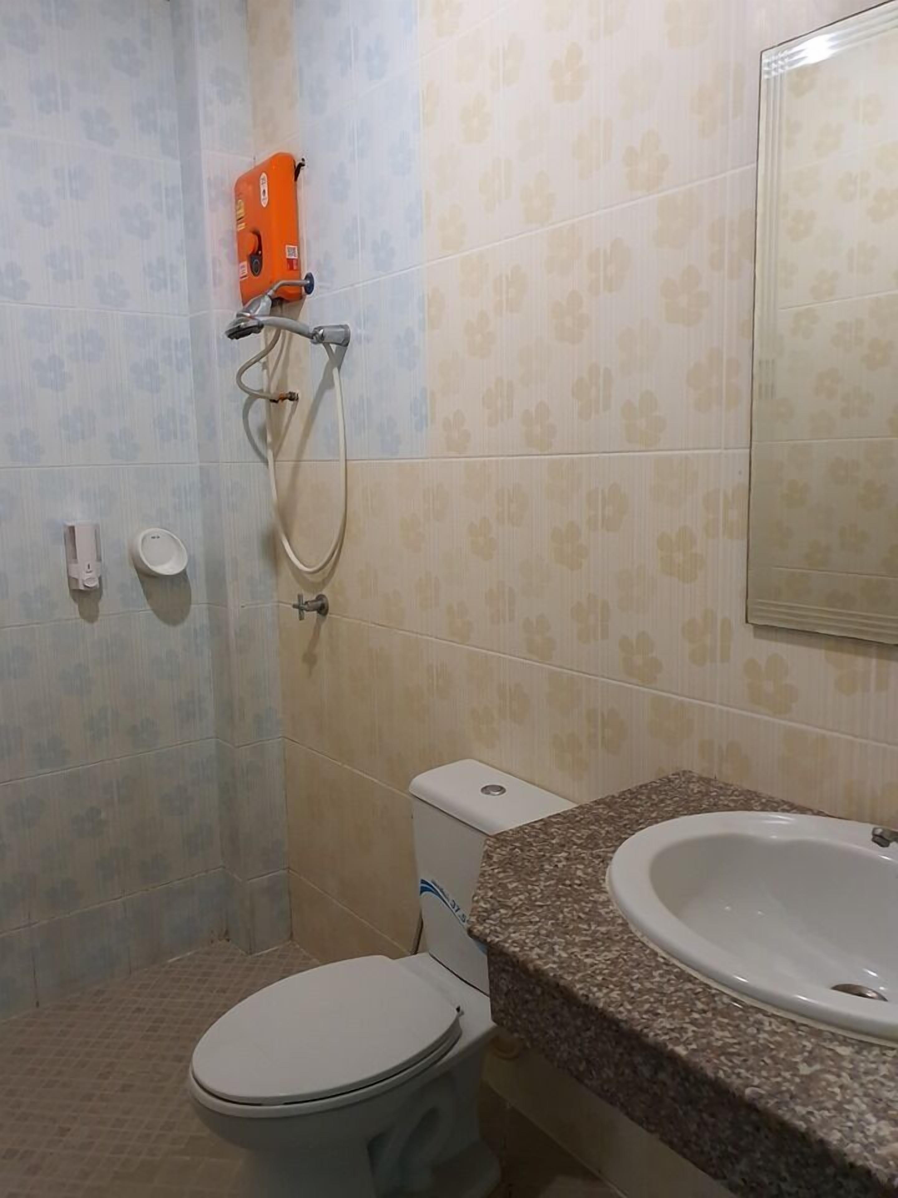 A bathroom with a toilet, a sink, a shower, and a hand dryer.