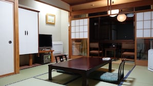 Une pièce de style japonais traditionnel, avec un sol recouvert de tatamis, une table basse, un téléviseur et un réfrigérateur.