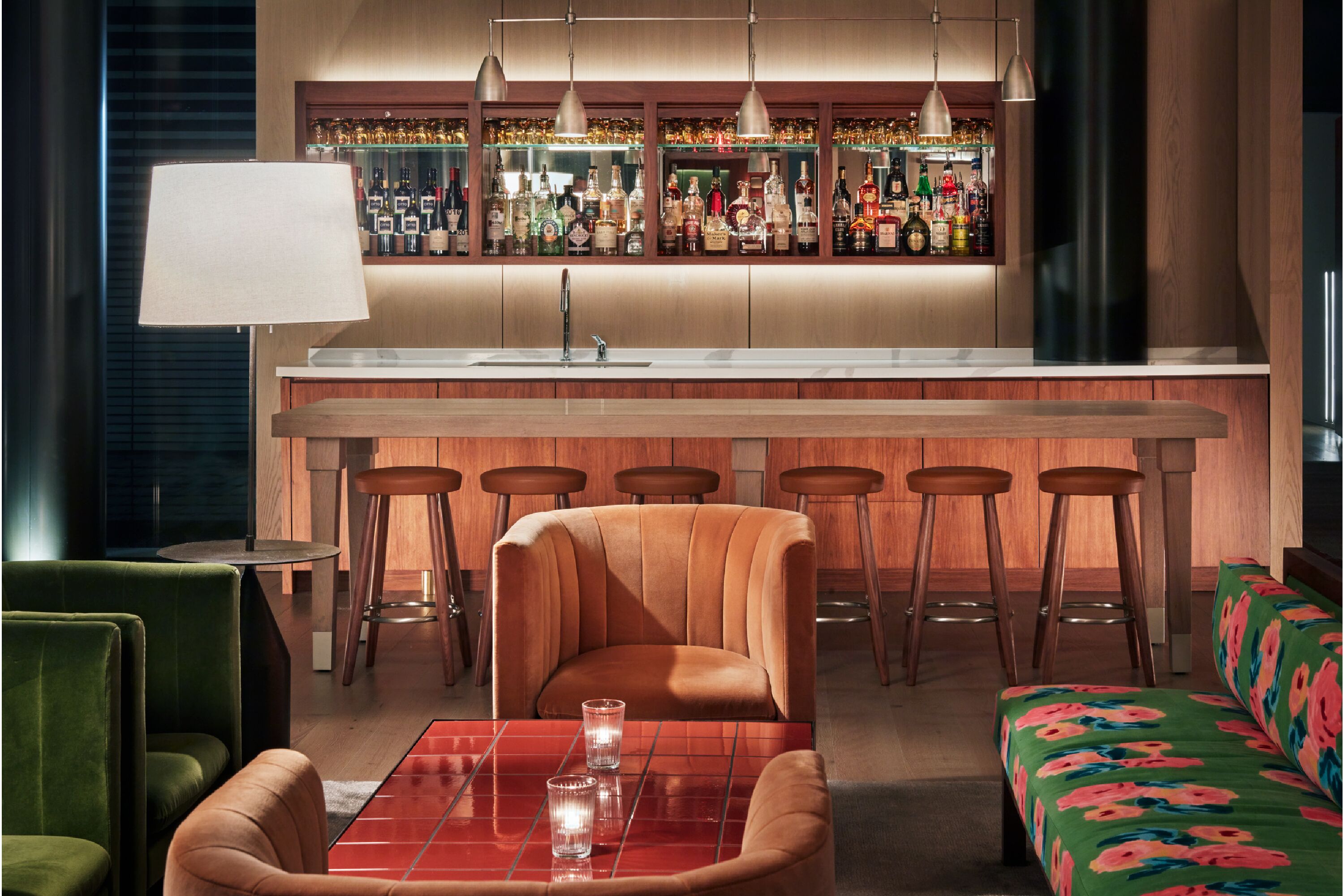 A bar area with stools, a bar counter, and a seating area with a sofa and chairs.