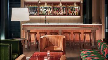 A bar area with stools, a bar counter, and a seating area with a sofa and chairs.