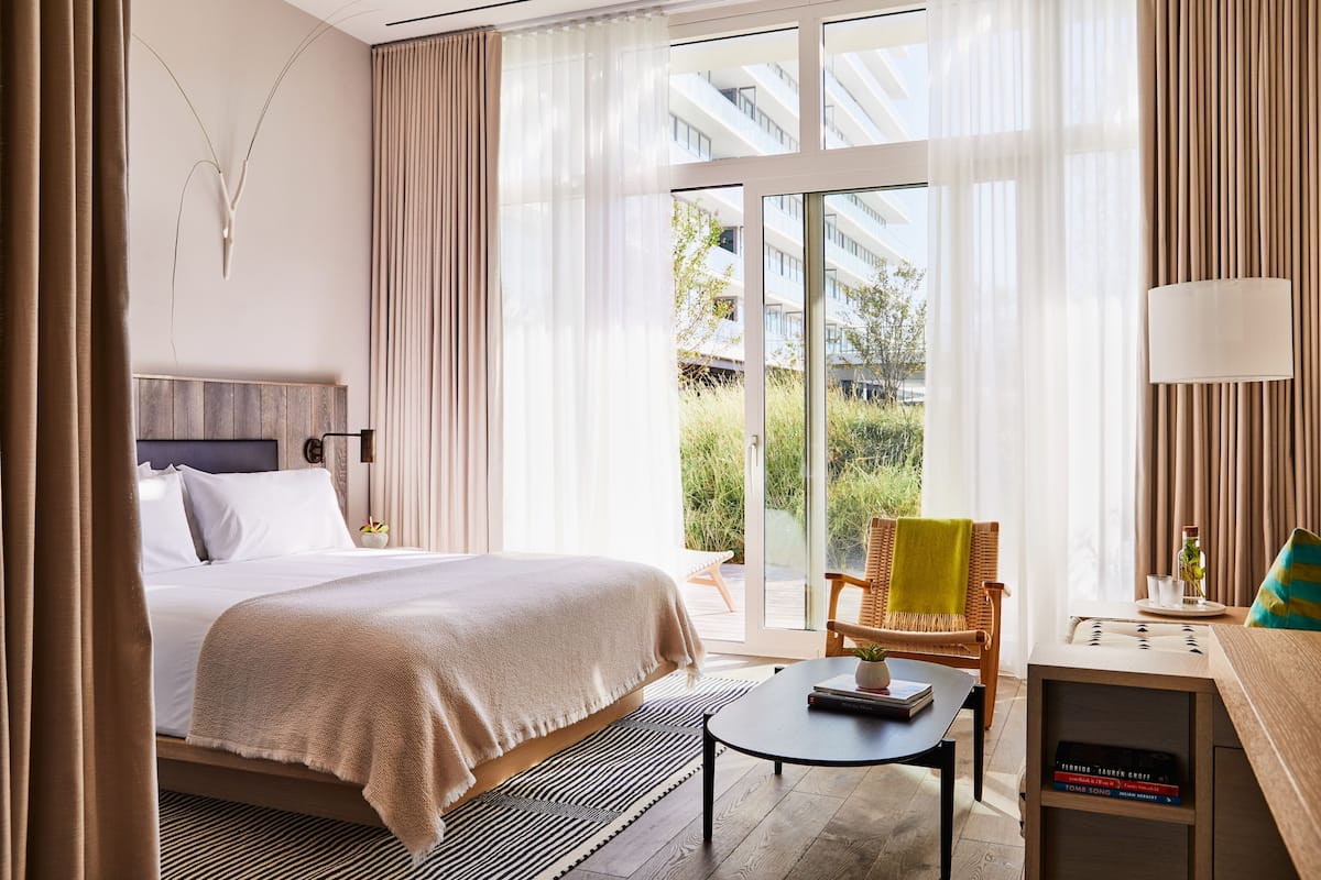 Ein Hotelzimmer mit einem Bett, einem Sessel, einem kleinen Tisch und einer Lampe.