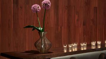 A modern bar area with a wooden wall, a vase with flowers, and bar stools.