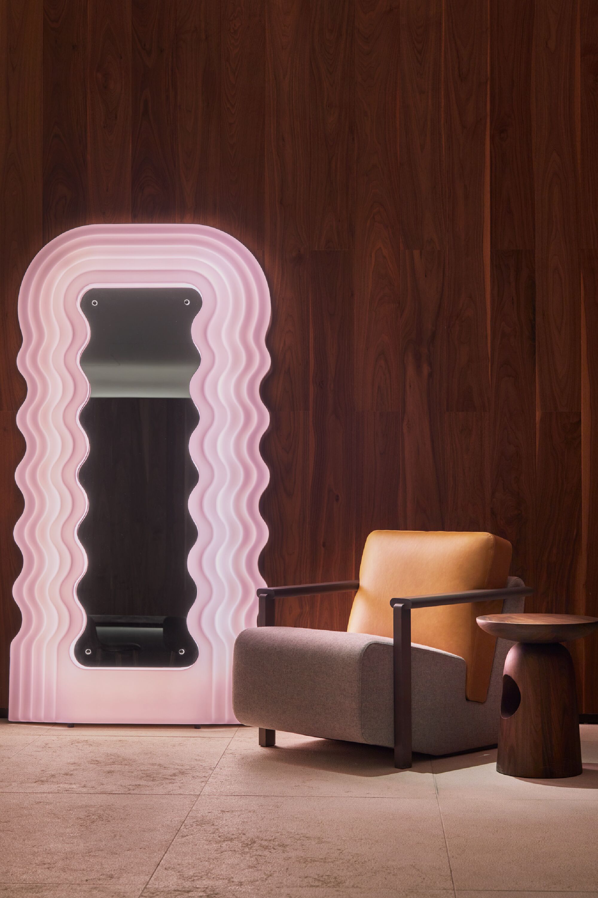 A room with a wooden wall, a pink and black object, a brown chair, and a small wooden table.