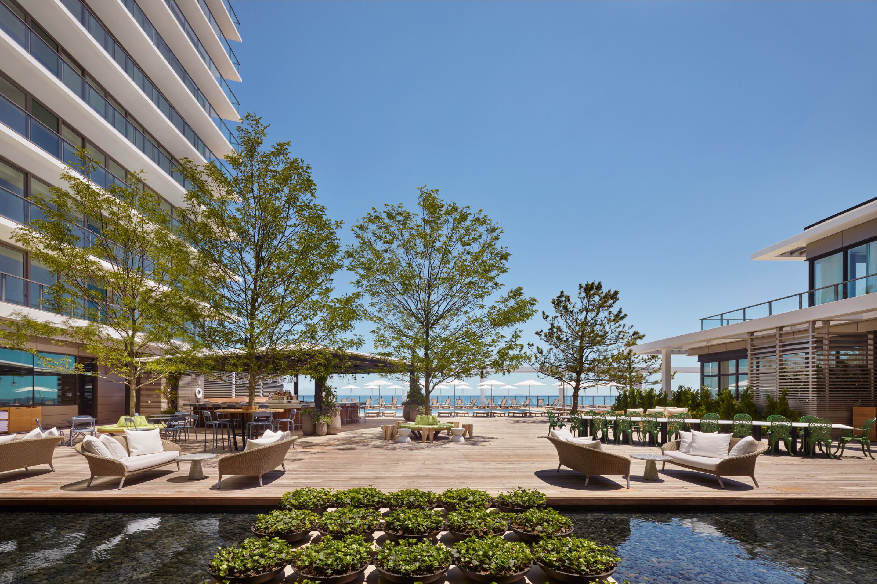 A rooftop pool area with outdoor seating and a view of the ocean.