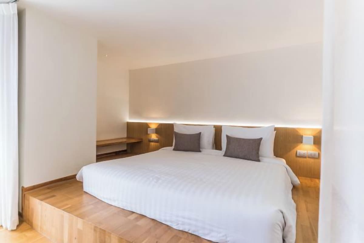 A hotel room with a large bed, bedside lamps, and a wooden platform.