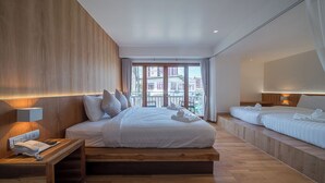 Una habitación de hotel moderna con una cama grande, una cama más pequeña, un escritorio con teléfono y un balcón con vistas a edificios.