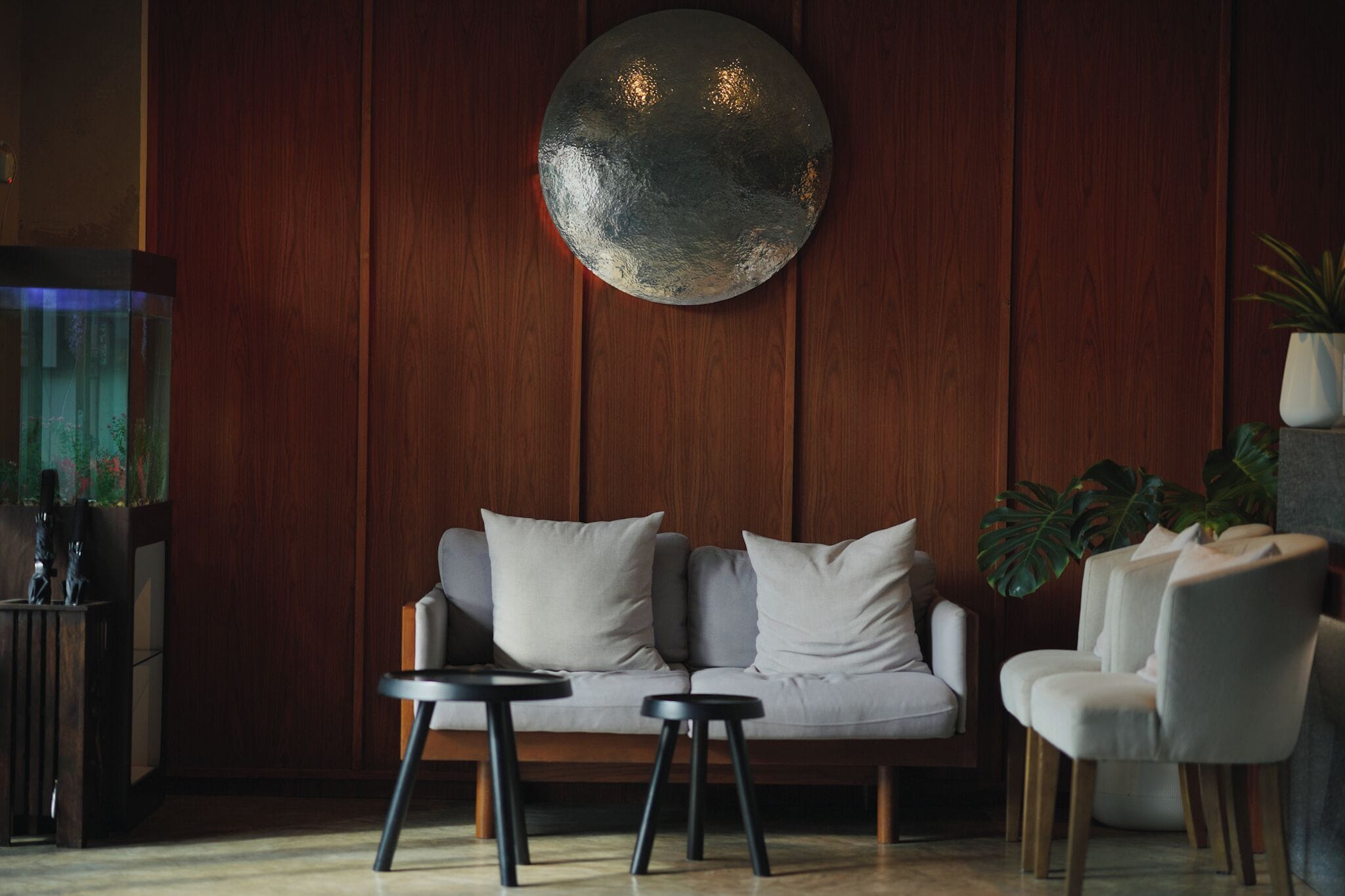A modern living room with a sofa, two side tables, and a round wall decoration.