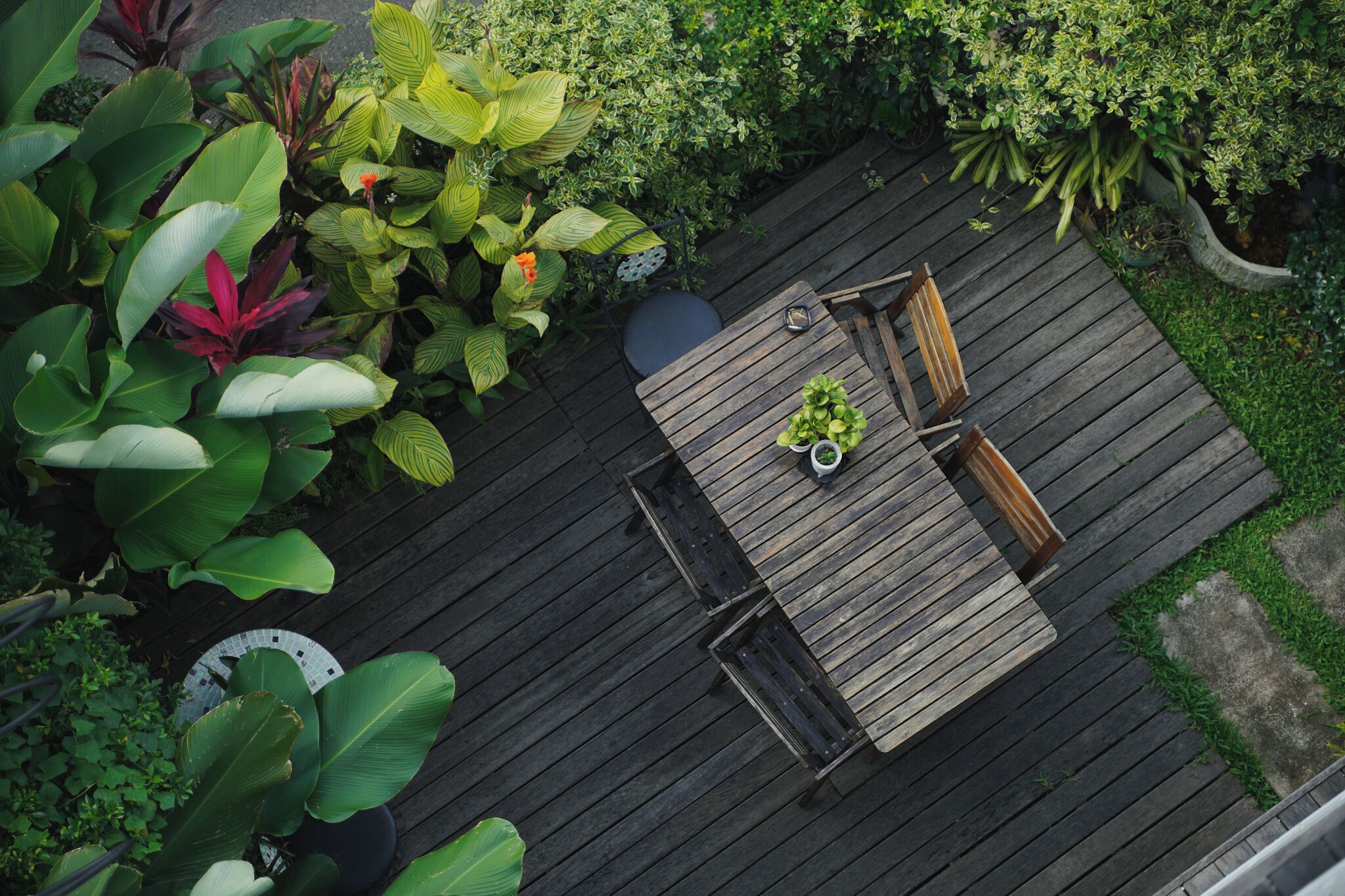 A wooden deck with a table and chairs, surrounded by lush greenery.