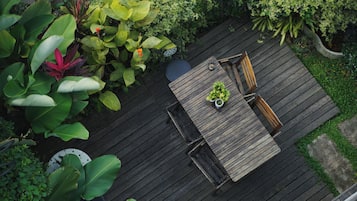 A wooden deck with a table and chairs, surrounded by lush greenery.