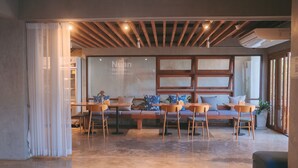 Un interior moderno con techo de madera, un conjunto de sofás y una zona de comedor con sillas y mesas.