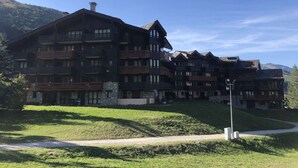 A multi-story hotel with balconies, stone facade, and a view of the surrounding landscape. - Athamante 60 - Large duplex, close to slopes and shops (LES AVANCHERS VALMOREL)
