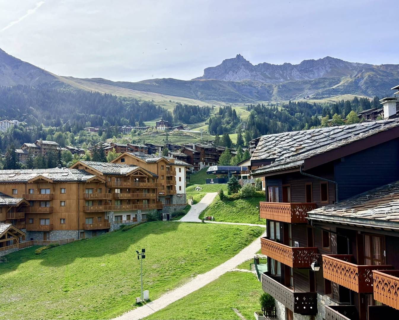 A mountain village with traditional wooden buildings, a clear path, and a view of the surrounding hills.