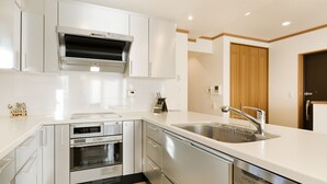 Une cuisine moderne avec des meubles blancs, des appareils en acier inoxydable et un four encastré.