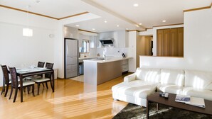 Une cuisine moderne dotée d’un îlot central, un coin repas avec une table et des chaises, et un espace de vie avec un canapé et une table basse.