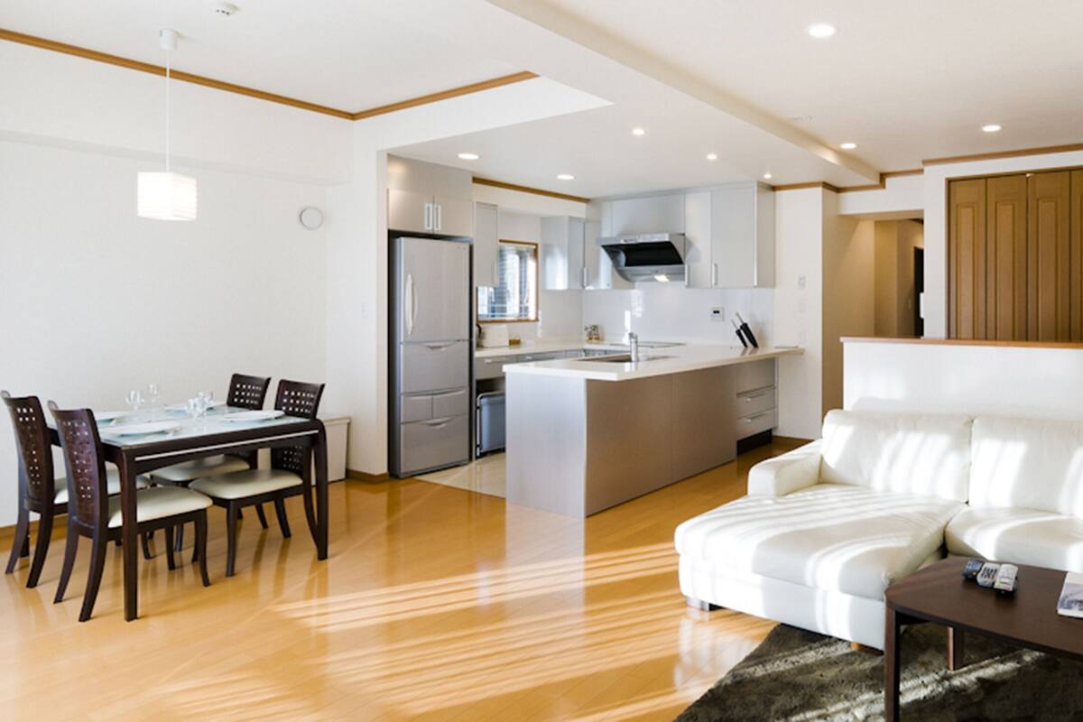 A modern kitchen with a central island, a dining area with a table and chairs, and a living area with a sofa and coffee table.