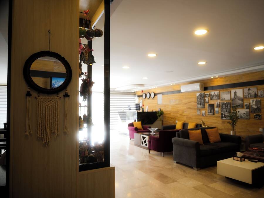 Um hall moderno com balcão de recepção em madeira, área de estar confortável e parede decorada com quadros.