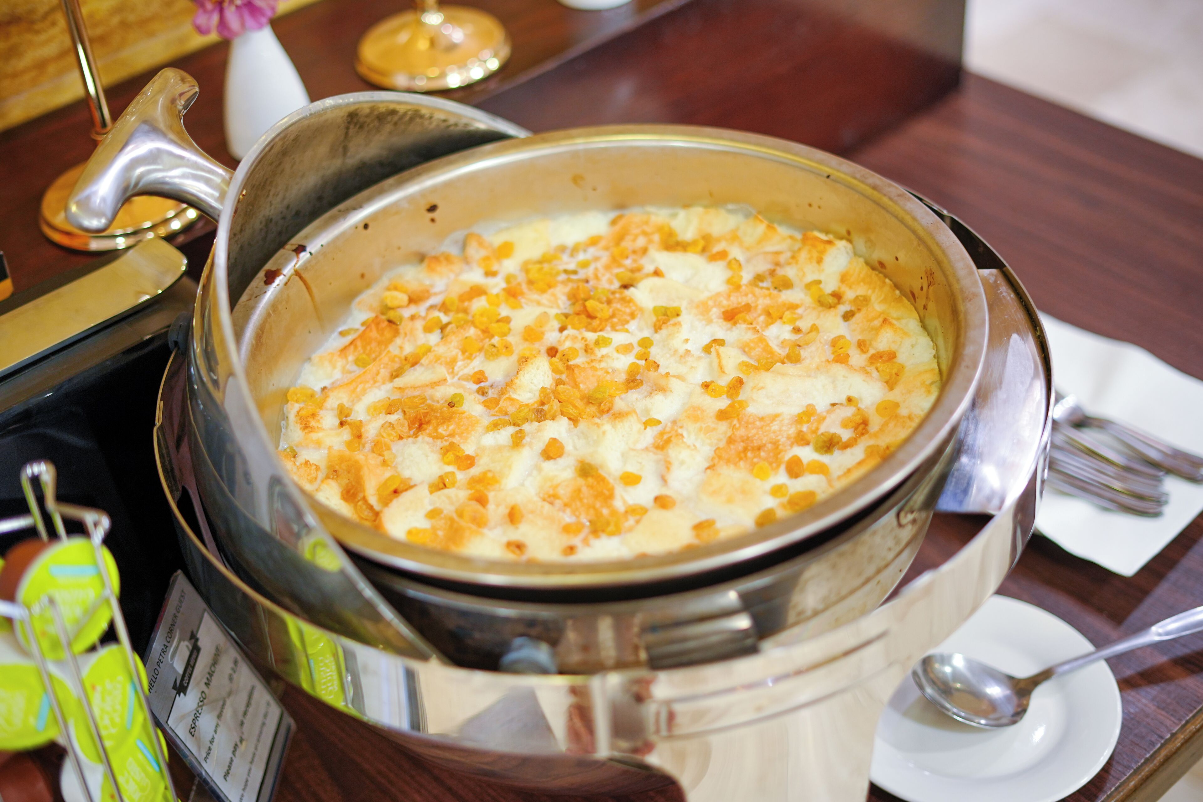 Un plat de fondue, agrémenté de maïs et de fromage, servi dans un récipient en métal sur une table en bois.