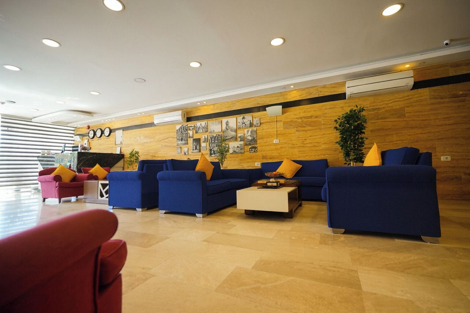 Een moderne lobby met blauwe banken, een rode fauteuil en een salontafel.