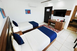 Habitación de hotel con dos camas, un escritorio, un televisor y una puerta.