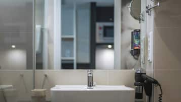 A bathroom with a white sink, a mirror, and a hairdryer on the counter.