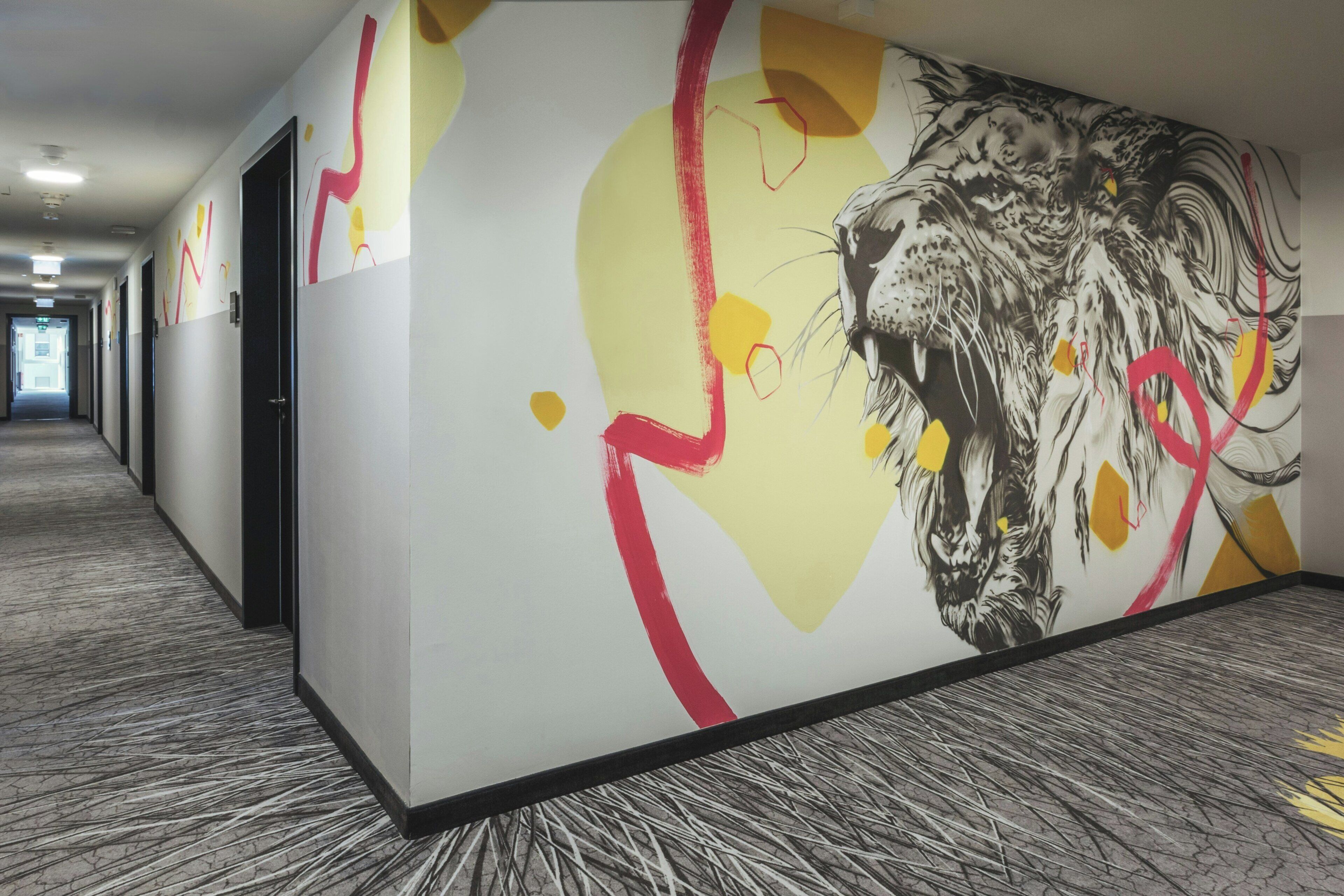 A hallway with a large abstract painting on the wall, a patterned carpet, and doors leading to rooms.