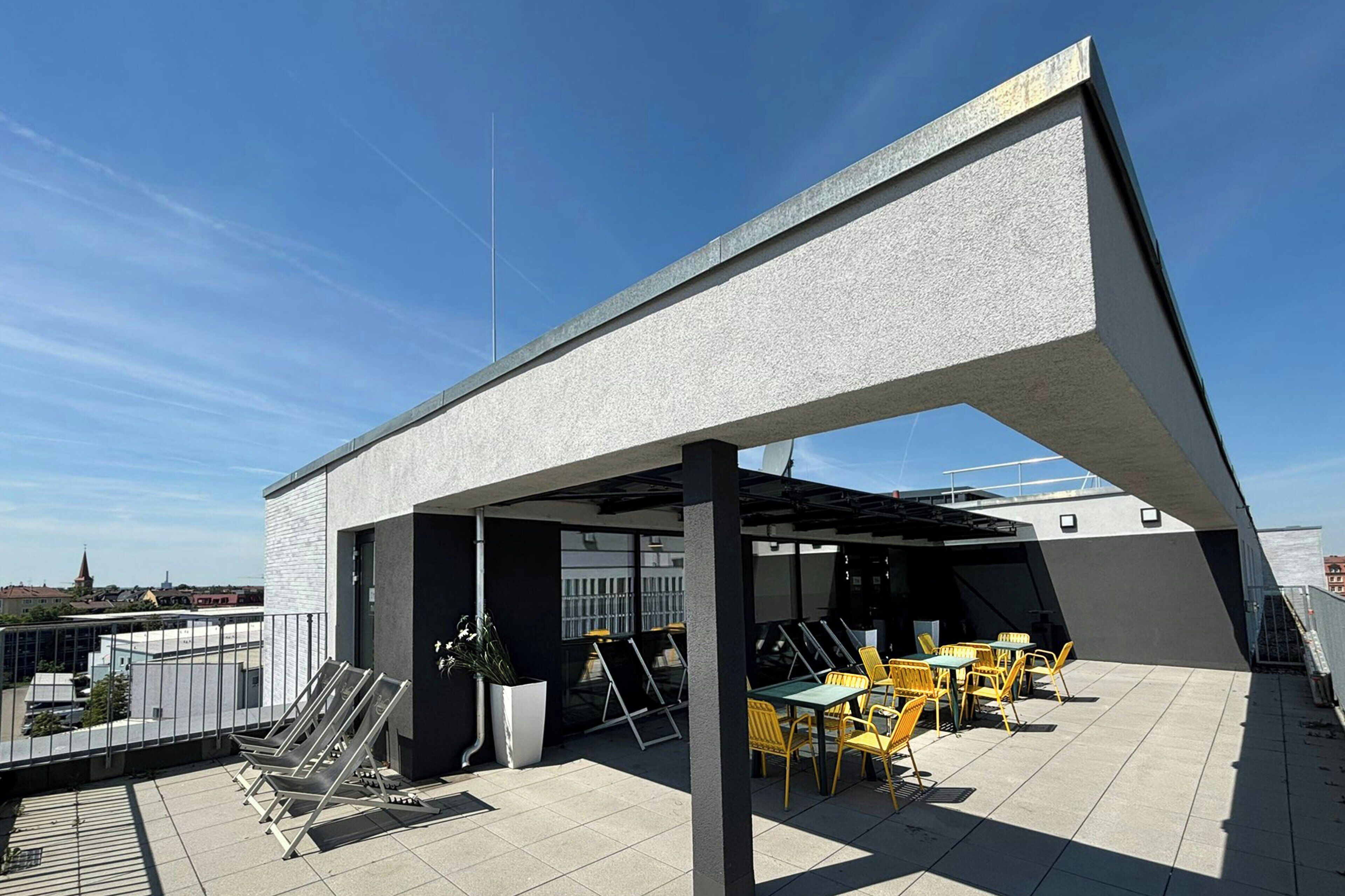 An outdoor seating area with tables and chairs, a metal staircase, and a building with a sloped roof.