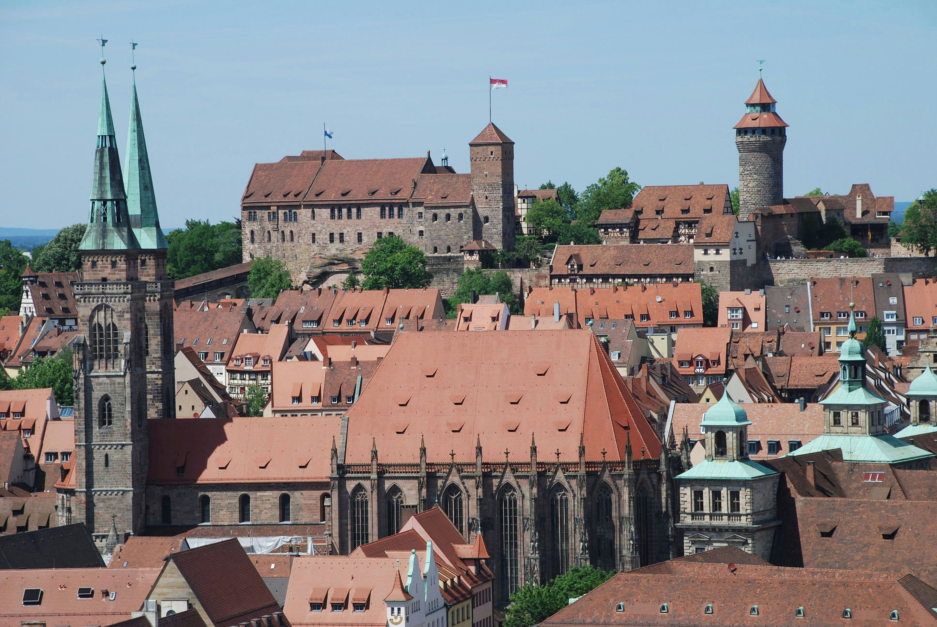 A historic town with medieval architecture, including a prominent church with a tall spire and a castle-like structure with a red roof.