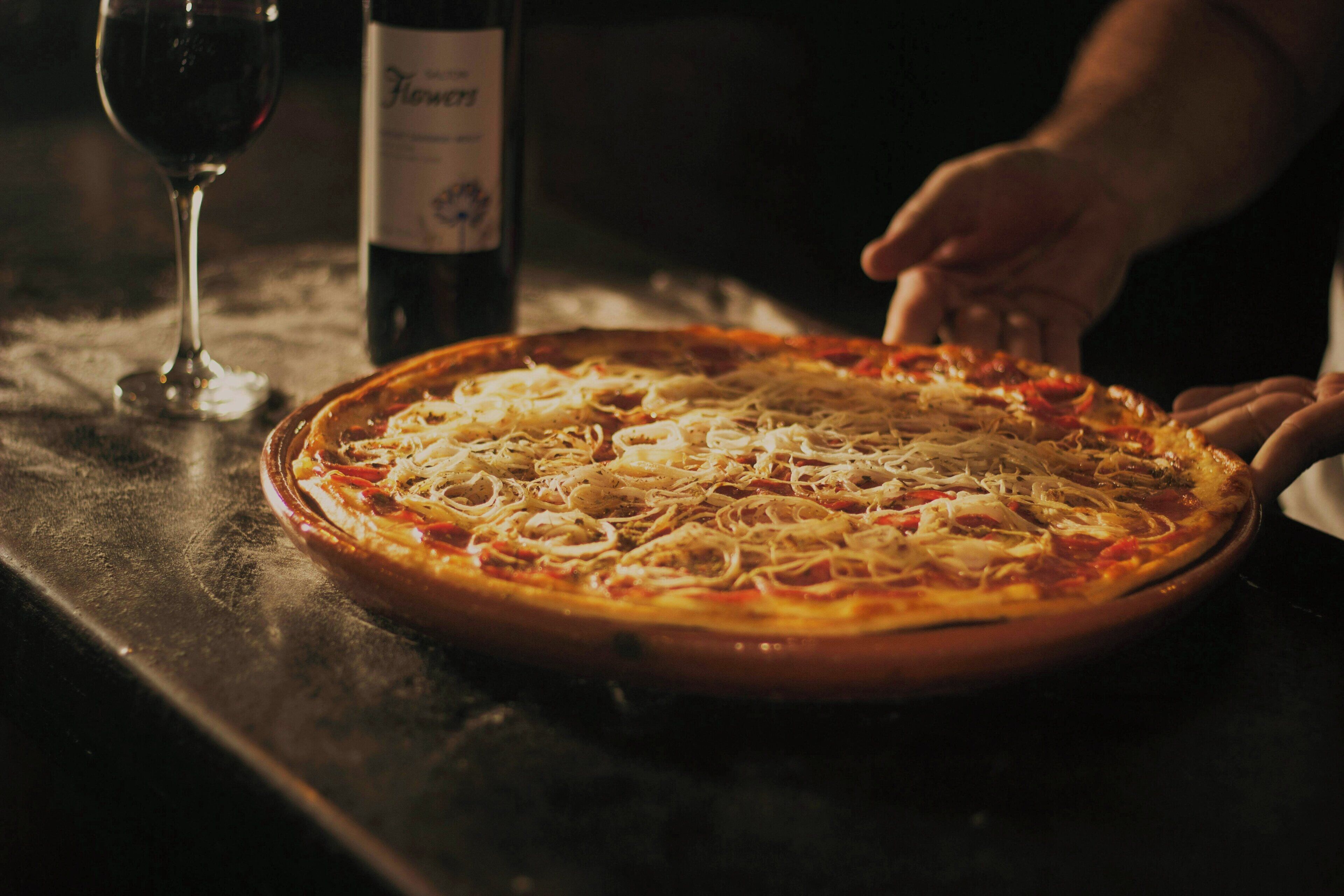Pizza op een tafel met een fles en een glas wijn.