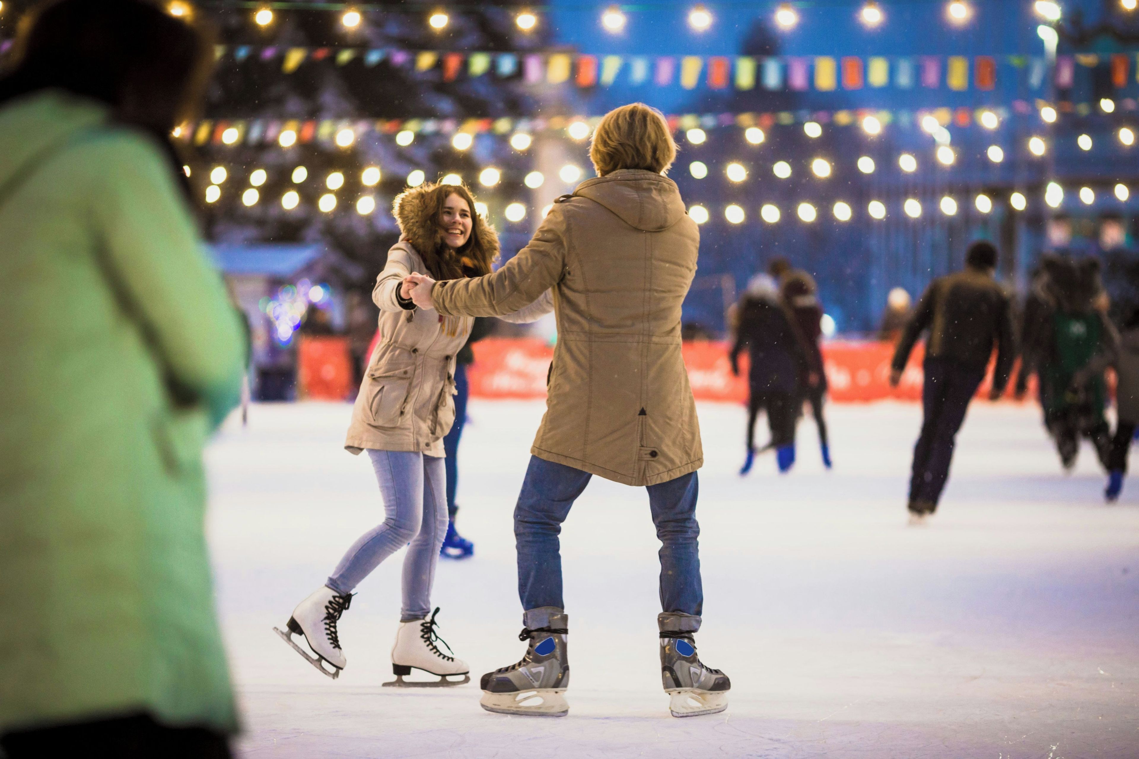 Menschen laufen auf einer festlich geschmückten Eisbahn.