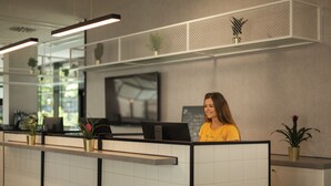 Un área de recepción de diseño moderno, con mostrador de recepción, televisor de pantalla plana y plantas en macetas.