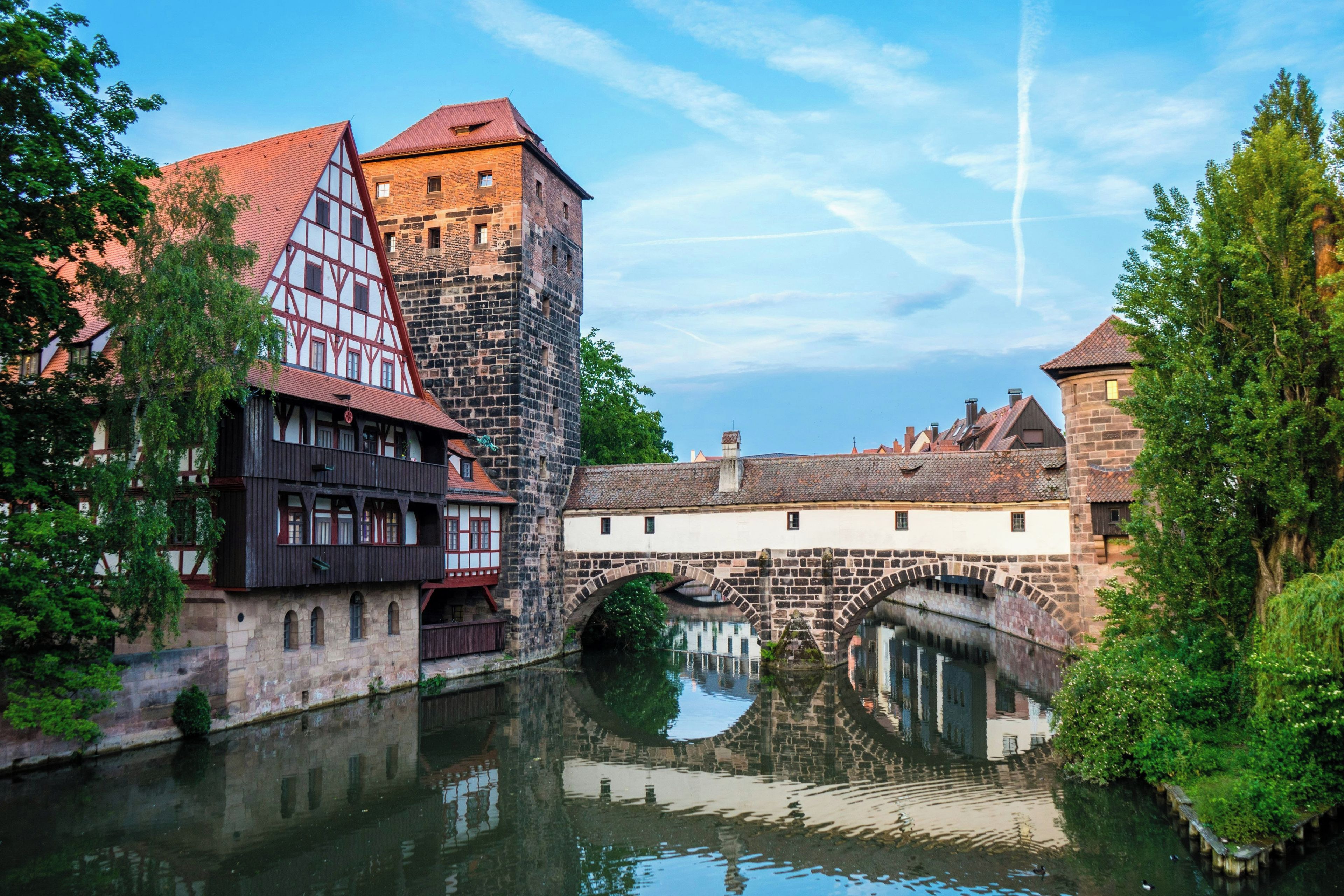 A historic town with traditional architecture, a river, and a stone bridge.
