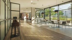 Un interior moderno con una zona de bar, asientos y ventanas amplias que ofrecen vistas al exterior.