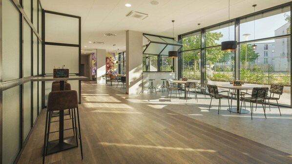 Un interior moderno con una zona de bar, asientos y ventanas amplias que ofrecen vistas al exterior.