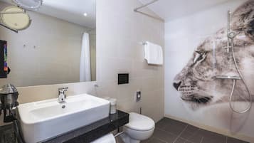 A modern bathroom with a large mirror, a sink, a toilet, and a shower.
