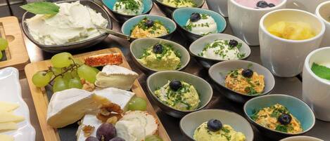 A variety of cheeses and fruits on a table.