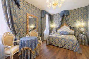 A bedroom with a large bed, a vanity with a mirror, a table, and chairs. - Canal View San Marco Luxury Rooms (Venice)